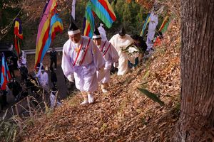 権立達は、落ち葉が積もる山道へ。幡行列は、下の舗装道路を進む。