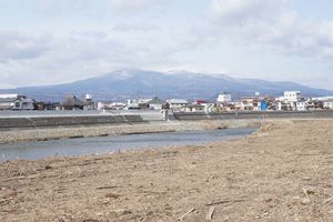 阿武隈川が溢れ、対岸では堤防のかさ上げが行われている（白っぽい部分がそれ）。