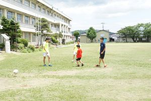 小学校のグラウンドで汗を流す、仲良し小・中学生。