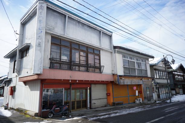 建物の角に、縦で「肉とハキモノの店」と薄っすら読める。