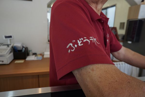 腕に看板商品「ぶどう氷」の名が入ったポロシャツが制服がわり。